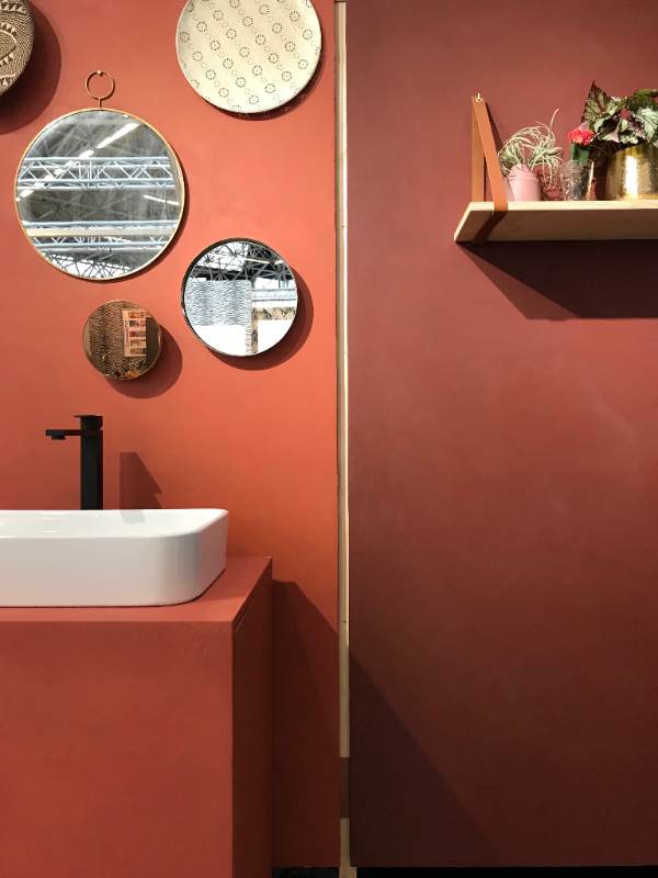Beton ciré wanden in kleur Chili en Vuur bekleed met diverse spiegels en badkamermeubel bedekt met beton ciré.